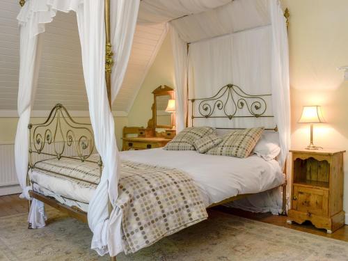 een slaapkamer met een wit bed en een baldakijn bij Trem Yr Ynys in Betws-y-coed