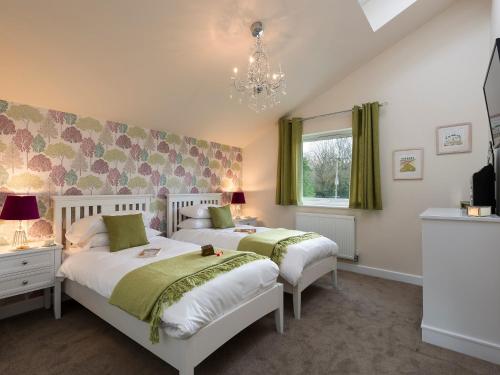 a bedroom with two beds and a chandelier at The Haybarn in Ferndown