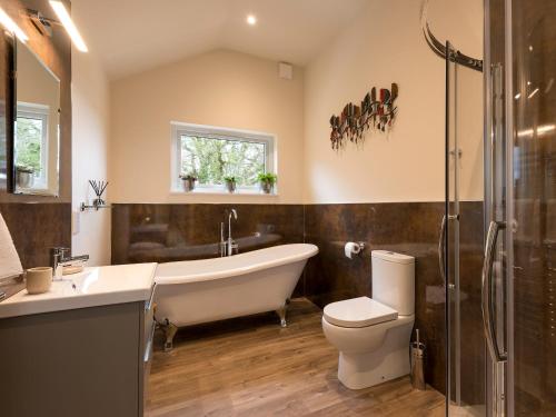 a bathroom with a tub and a toilet and a sink at The Haybarn in Ferndown