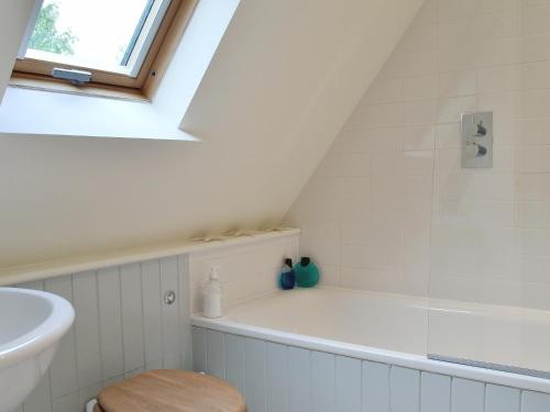 a bathroom with a bath tub and a sink at Brookside Cottage in Burley
