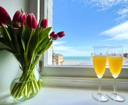 two glasses of wine and flowers on a window sill at Bright, Seaview Apartment, Beachfront, 3 bedrooms, 2 bathrooms, kid & dog friendly at The Lookout Broadstairs in Broadstairs