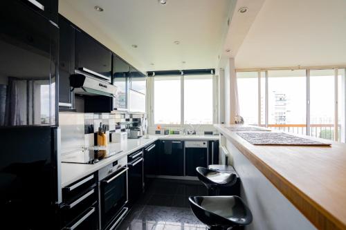 une cuisine avec des placards noirs et un comptoir avec des tabourets dans l'établissement 2-pièces ensoleillé, 5 min du metro, à Villejuif