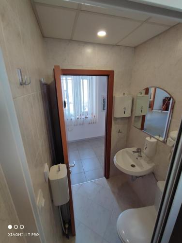 a bathroom with a sink and a toilet and a mirror at Hostel CANTO in Ruse