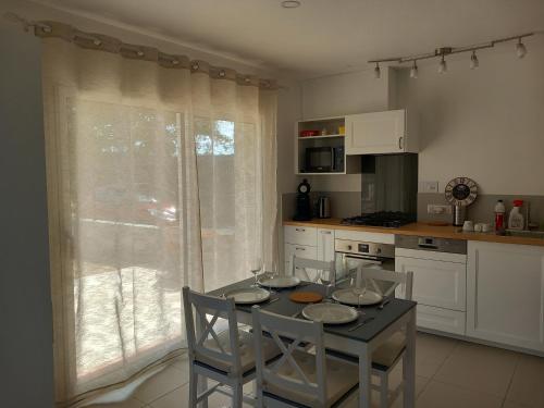 une cuisine avec une table et quatre chaises ainsi qu'une fenêtre dans l'établissement Le calme au milieu des vignes, à Vidauban