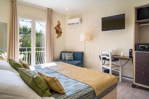 a bedroom with a bed and a desk and a television at Hotel Rivage Taormina in Taormina