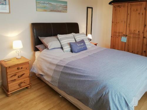 a bedroom with a large bed and a wooden dresser at Trevone in St Merryn