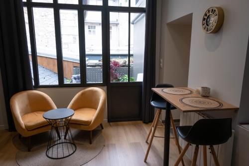 une chambre avec des chaises, une table et une fenêtre dans l'établissement L'instant léger - Centre ville, à Chambéry