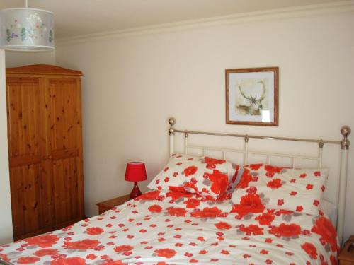 Un dormitorio con una cama con flores rojas. en Fleet Cottage, en Portree