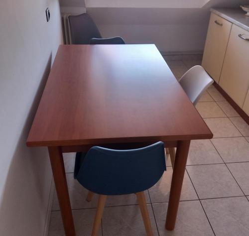 einen Holztisch in einer Küche mit zwei blauen Stühlen in der Unterkunft Romano's House in Castel di Lama