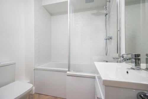 a white bathroom with a shower and a sink at Gainsborough Studio, Sudbury in Sudbury