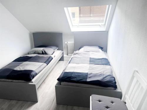 two beds in a small bedroom with a window at Comfy Apartment in Krefeld in Krefeld