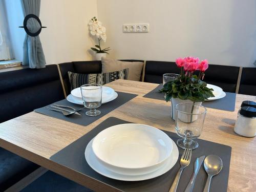 a table with plates and glasses and a vase of flowers on it at Gästehaus Trockau in Pegnitz
