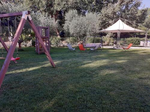 a swing set in a yard with chairs and an umbrella at LE CERQUE in Spoleto