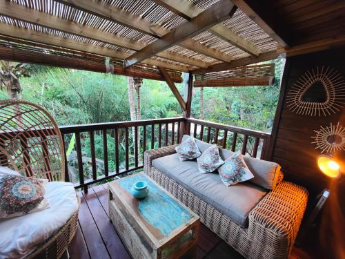 a porch with two wicker chairs and a table at OHANA Jungle Lodges in Les Avirons