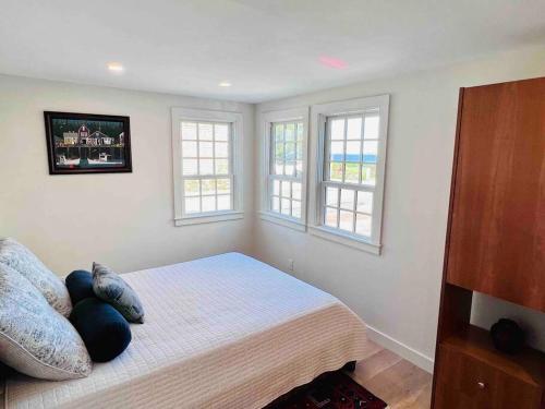 a bedroom with a bed with two pillows and two windows at Historic 2 Bedroom with marble baths and water views in Newburyport