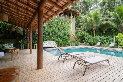 una terraza con piscina y sillas junto a una casa en Pousada Recanto do Sol, en Trancoso