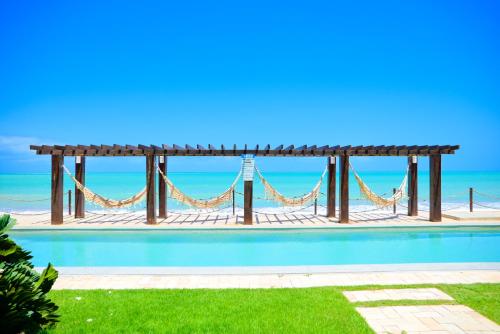 a swimming pool with a hammock and the ocean at Waterfront Residence in Maceió