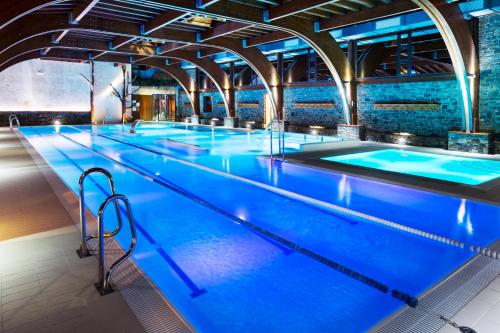 a row of an indoor swimming pool with blue water at Hotel AnyosPark Mountain & Wellness Resort in Anyós