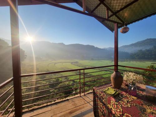 a balcony with a table and a view of a valley at Moc's House in Bắc Hà