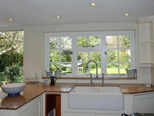 una cucina con lavandino e due finestre di The Bothy a Lymington