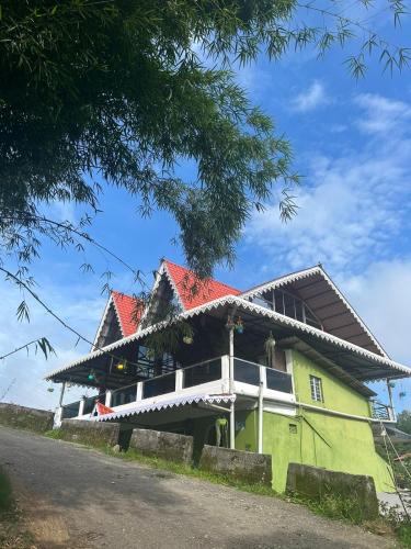 a green house with a red roof on a road at Mirik Homestay in Mirik