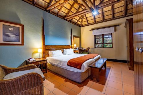 a bedroom with a bed and a chair in a room at Pestana Kruger Lodge in Malelane