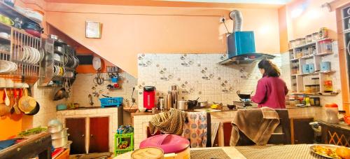 a woman standing in a kitchen preparing food at Mirik Homestay in Mirik