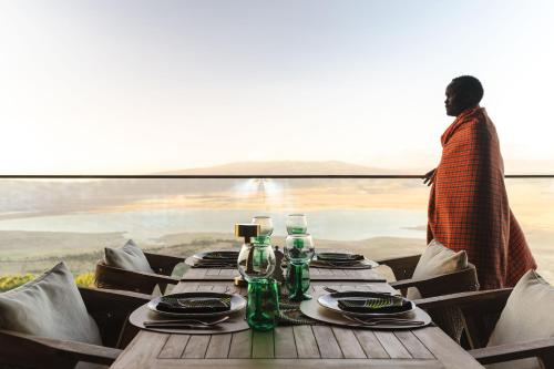 a woman standing behind a wooden table with plates and bottles at Ngorongoro Lodge member of Melia Collection - The Leading Hotels of the World in Ngorongoro