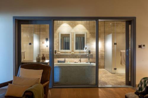 a bathroom with a tub in a room with a chair at Ngorongoro Lodge member of Melia Collection - The Leading Hotels of the World in Ngorongoro