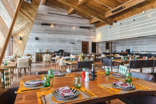 Ngorongoro Lodge member of Meliá Collection في نجورونجورو: غرفة طعام مع طاولات وكراسي خشبية