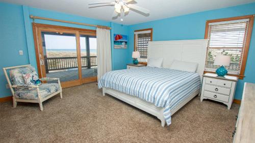 a bedroom with a bed and a chair and a window at Oceanfront, Wild Horses, Ocean Views, Private Pool, 4x2251, Beauty & The Beach in Knotts Island
