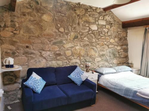 a bedroom with a blue couch and a stone wall at Hendy in Waenfawr