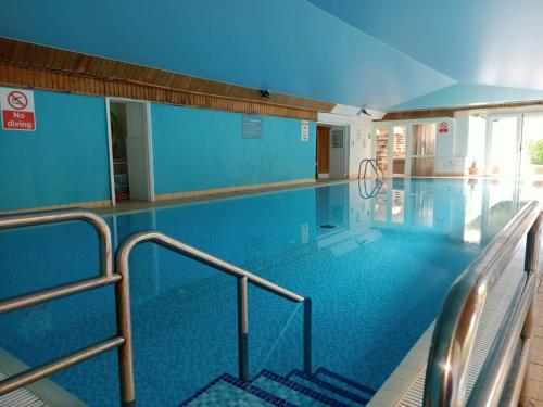 a large swimming pool with stairs in a building at Holbrook Manor & Spa in Wincanton