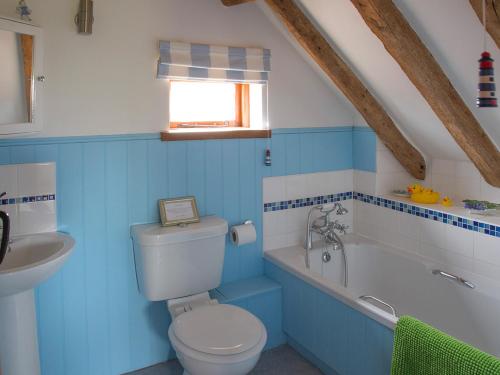 a blue bathroom with a toilet and a sink at Henrys Barn - Ukc3168 in Walpole