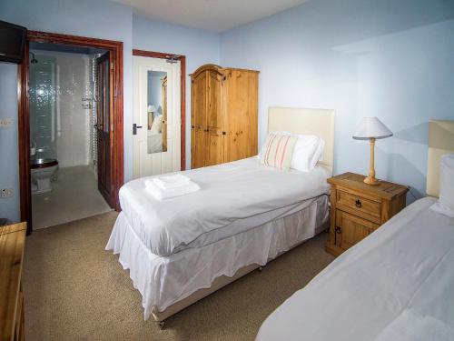 a bedroom with two twin beds and a bathroom at Kingfisher Barn in Sculthorpe