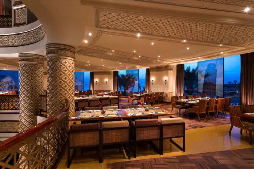 a restaurant with tables and chairs and a large window at Rosewood Jeddah in Jeddah