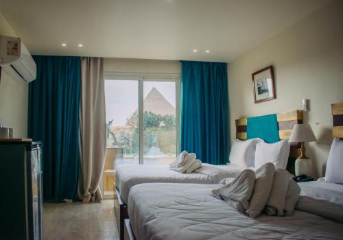a hotel room with two beds with a view of the pyramids at Great Pyramid Inn in Cairo