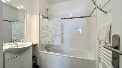 La salle de bains blanche est pourvue d'un lavabo et d'une baignoire. dans l'établissement Ma cabane de plage, à Saint-Valery-sur-Somme