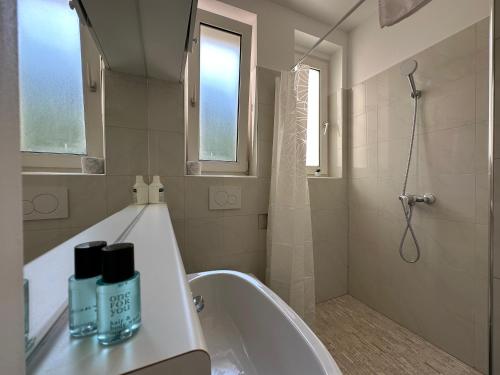 FeelHome-GolfClub-Balkon-4 Gäste-WiFi-Smart TV في إيبريتشسدورف: حمام مع حوض استحمام ودش ومغسلة