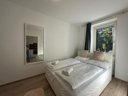 FeelHome-GolfClub-Balkon-4 Gäste-WiFi-Smart TV في إيبريتشسدورف: سرير أبيض في غرفة مع مرآة