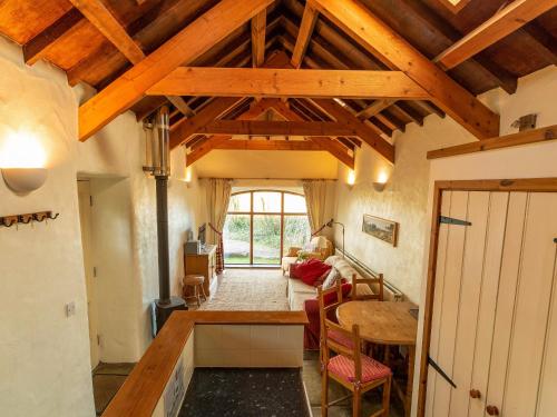 a kitchen and living room with wooden ceilings and a table at The Coach House in Mathry