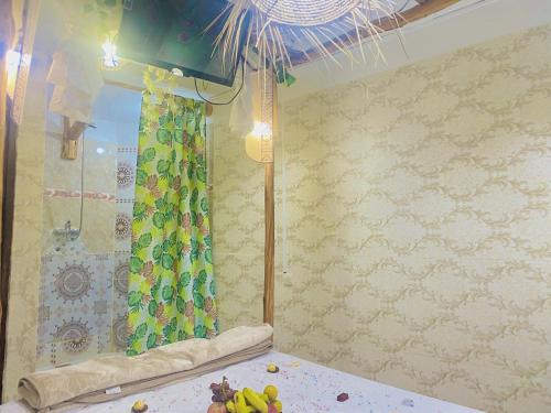 タガズートにあるTizaou Guest Houseのシャワーとフルーツが置かれたテーブルのある部屋