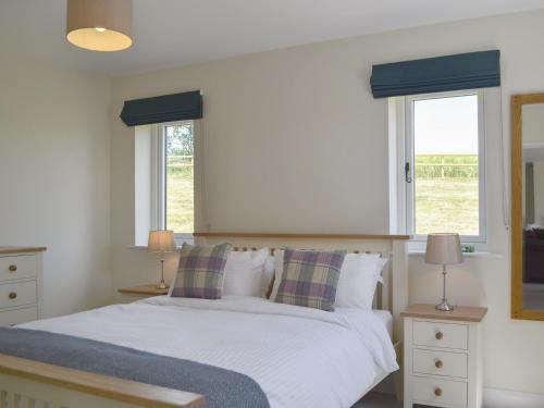 a bedroom with a white bed with two windows at Orchard Cottage in Morville