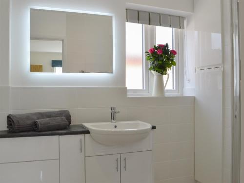 a white bathroom with a sink and a mirror at Orchard Cottage in Morville