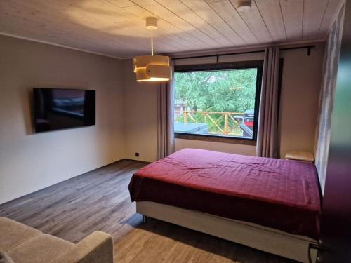 Schlafzimmer mit einem roten Bett und einem großen Fenster in der Unterkunft Tuorilan tupa in Jämsä