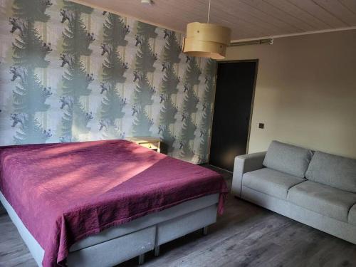 ein Schlafzimmer mit einem Bett und einem Sofa in der Unterkunft Tuorilan tupa in Jämsä
