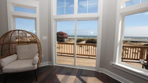 a wicker chair in a room with windows at Semi-Oceanfront, Ocean Views, Wild Horses, Private Pool, 4x2338, Race To The Beach in Knotts Island