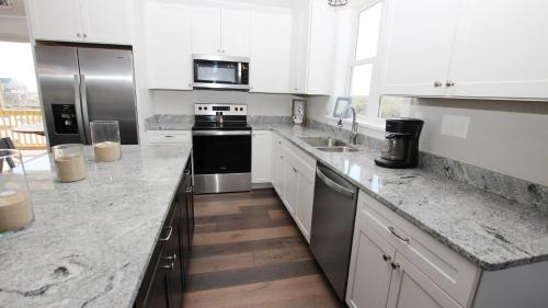 a kitchen with white cabinets and stainless steel appliances at Semi-Oceanfront, Ocean Views, Wild Horses, Private Pool, 4x2338, Race To The Beach in Knotts Island