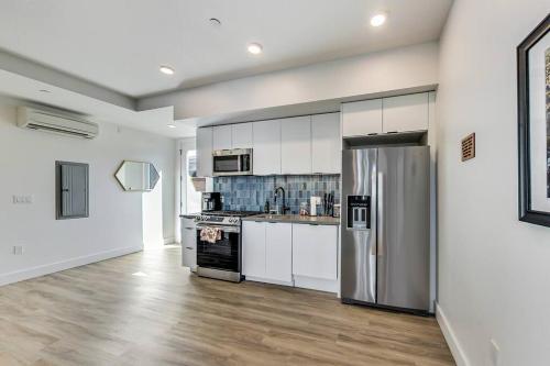 uma cozinha com armários brancos e um frigorífico de aço inoxidável em Brand New Luxury Fully Furnished Studio Suite em Oakland