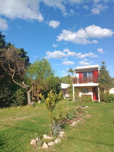 une maison dans un champ avec un arbre en face dans l'établissement Hermosa casa a 200 m de la playa, à Balneario Mar Chiquita